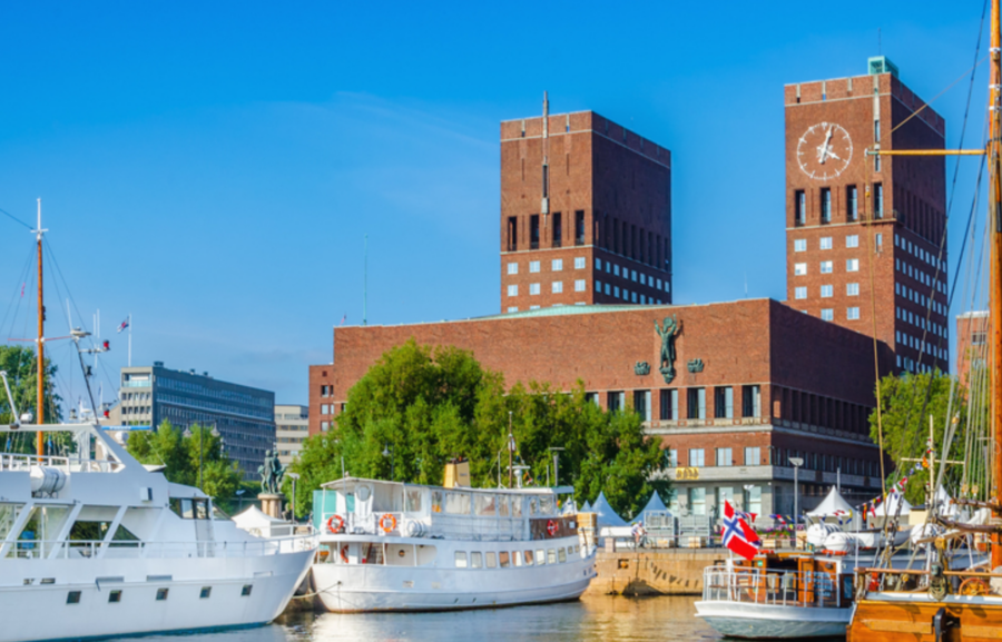 Bildet viser Rådhuset i Oslo fra sjøen med båter i forgrunn.