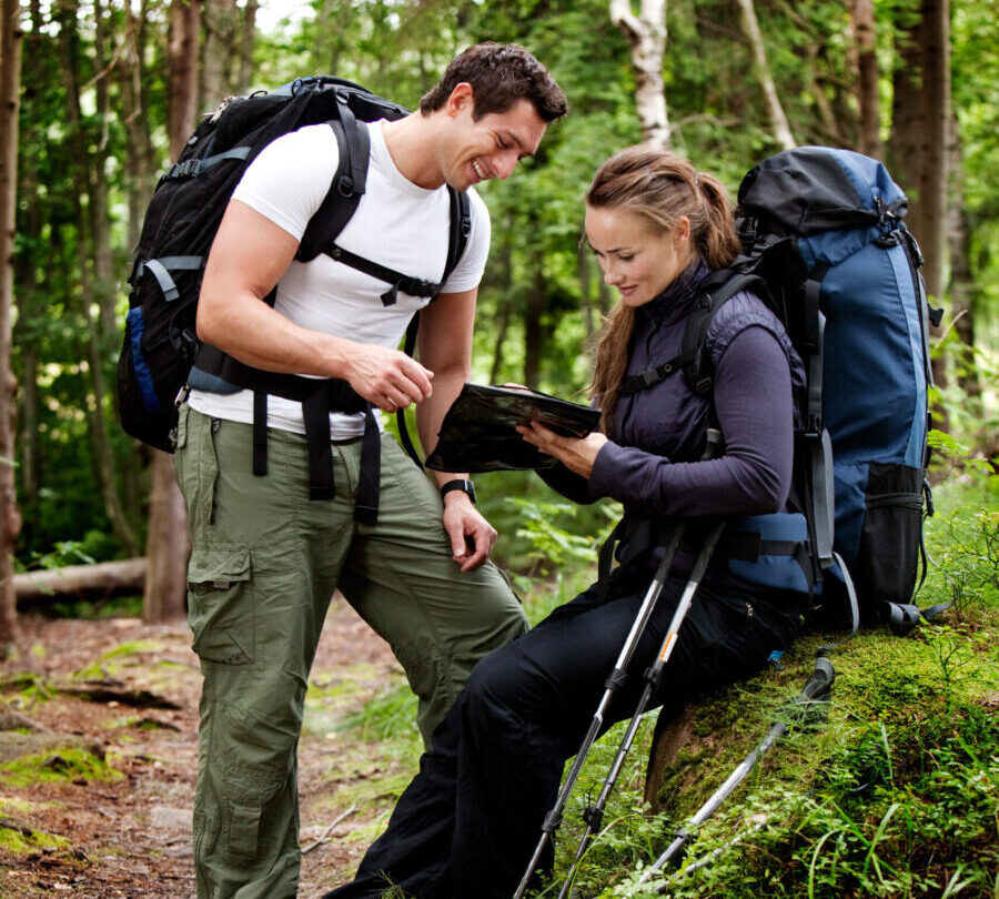 Bildet viser to mennesker på tur i naturen med ryggsekker og kart