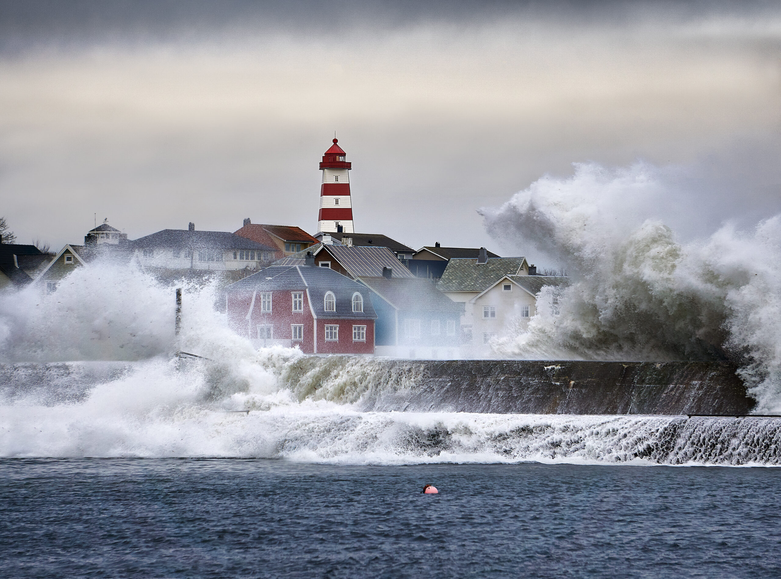 Storm sett fra sjøen mot Ålesund by med fyrtårn i bakgrunnen